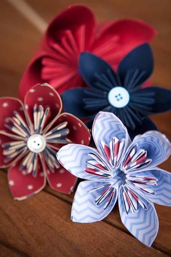 Paper flowers with buttons on wooden surface.