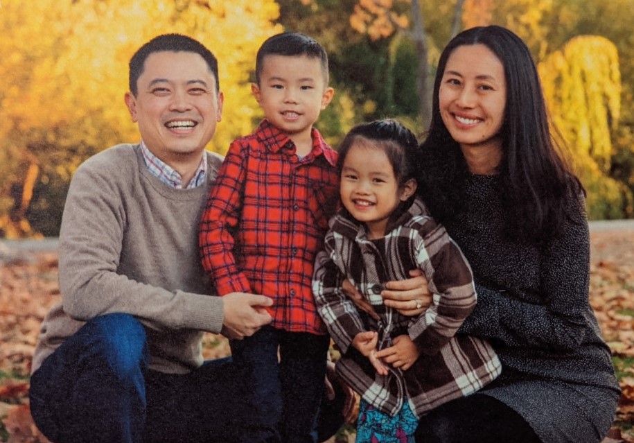 A family posing for a picture in front of trees.