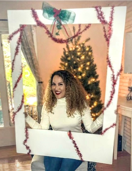 A woman standing in front of a christmas tree.
