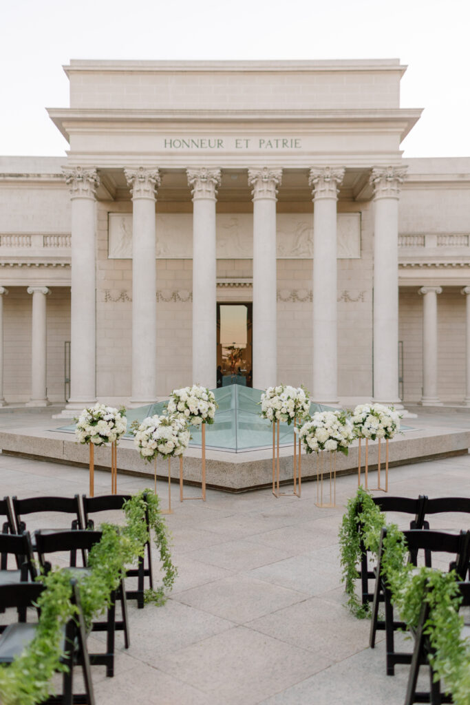A wedding ceremony with white flowers in front of the fountain.