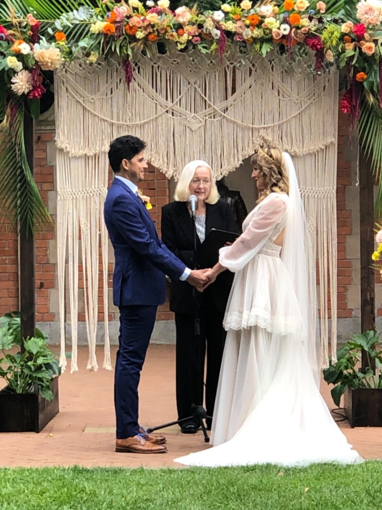 A couple getting married in front of an arch.
