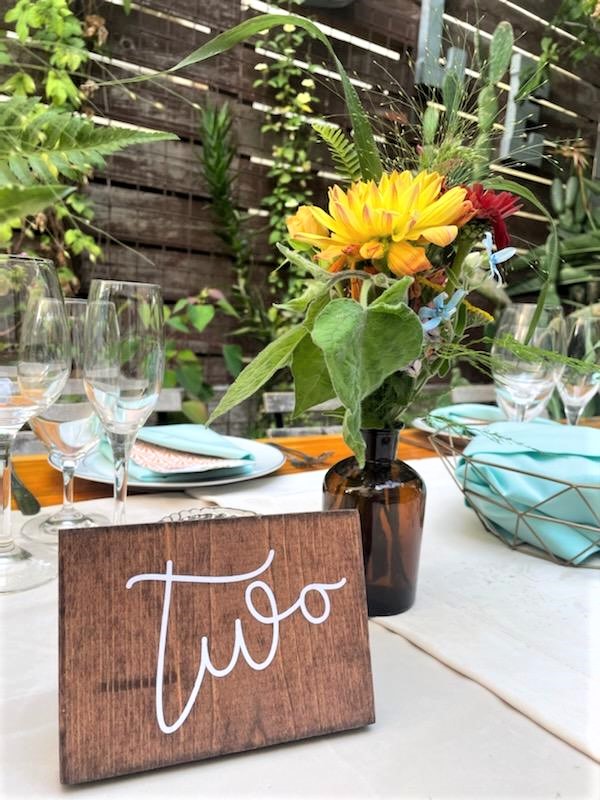 A table with two wooden signs and flowers.