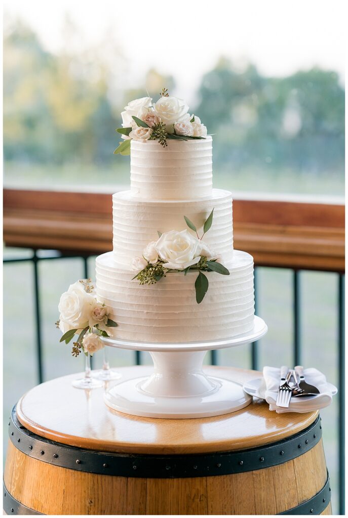 A three layer cake with white flowers on top of it.