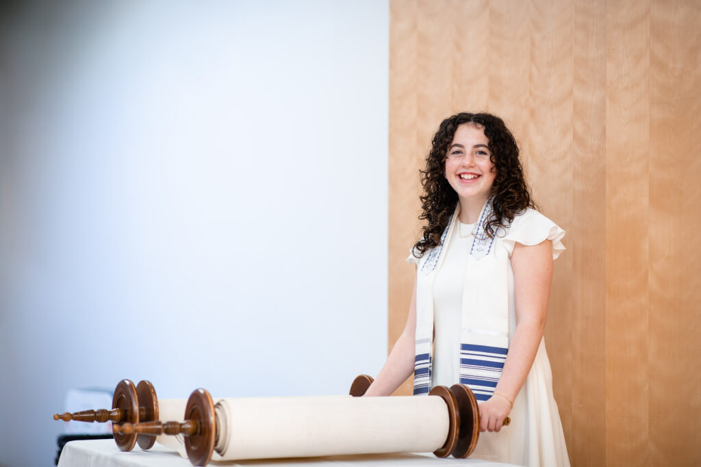 A woman standing next to a torah scroll.