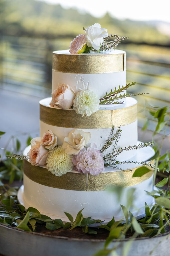 A three tiered cake with gold and white frosting.