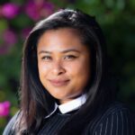 Christina A woman with long black hair wearing a suit.