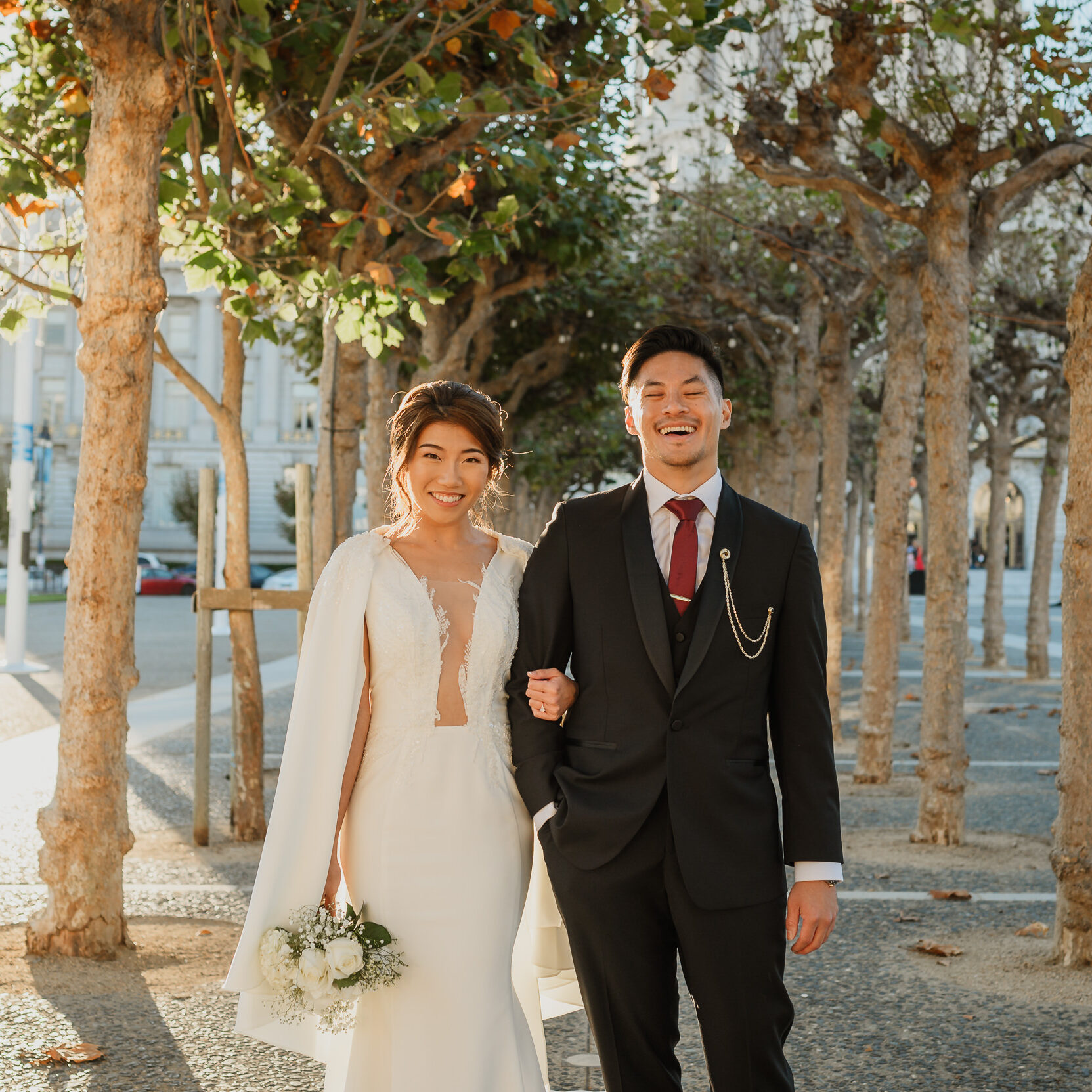 A man and woman posing for a picture in front of trees.