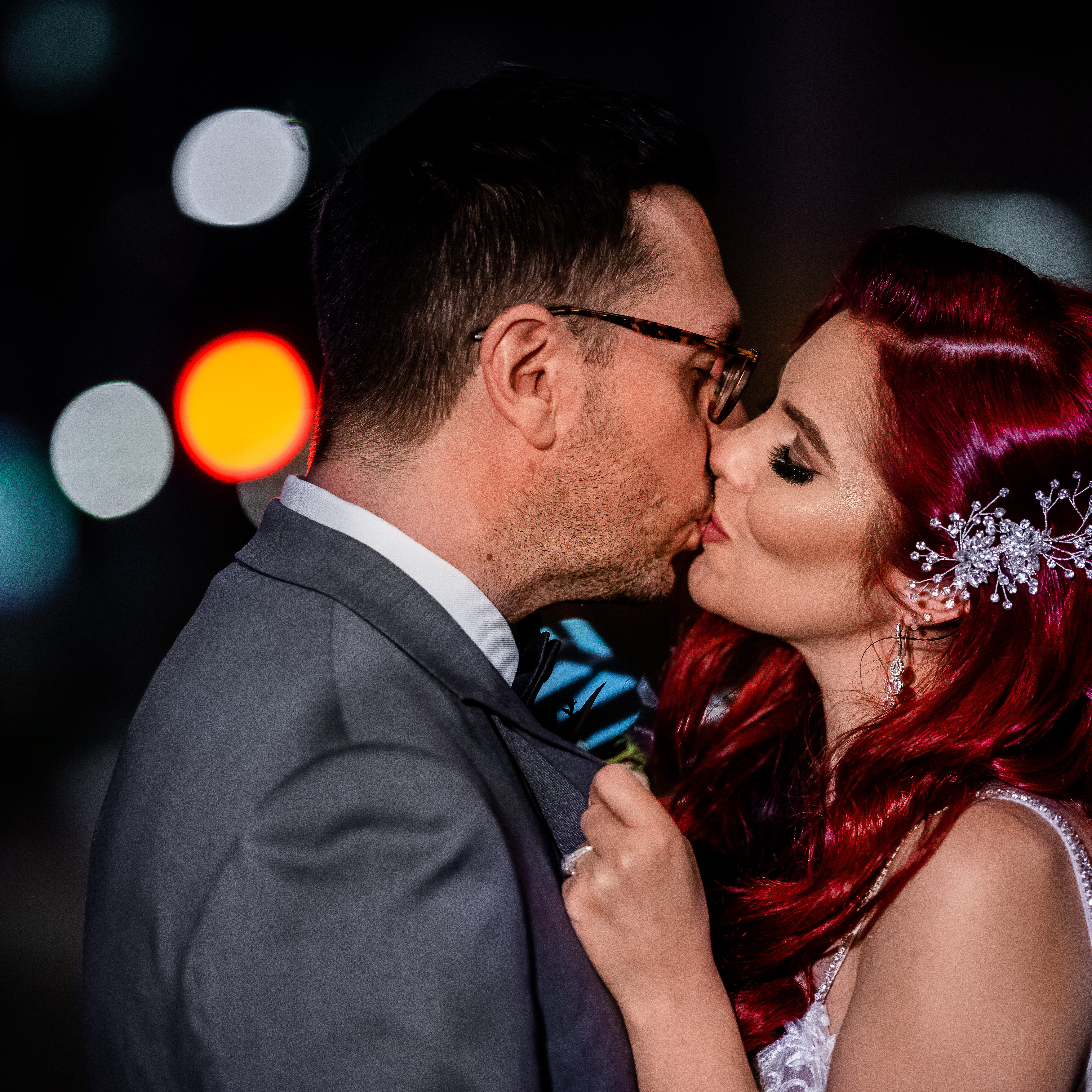 20190817-204228-7R305456 A man and woman kissing each other in front of lights.