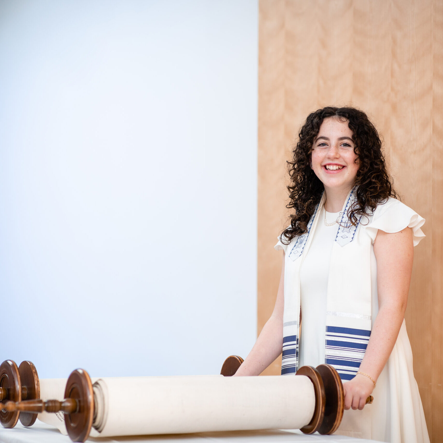 A woman standing next to a torah scroll.