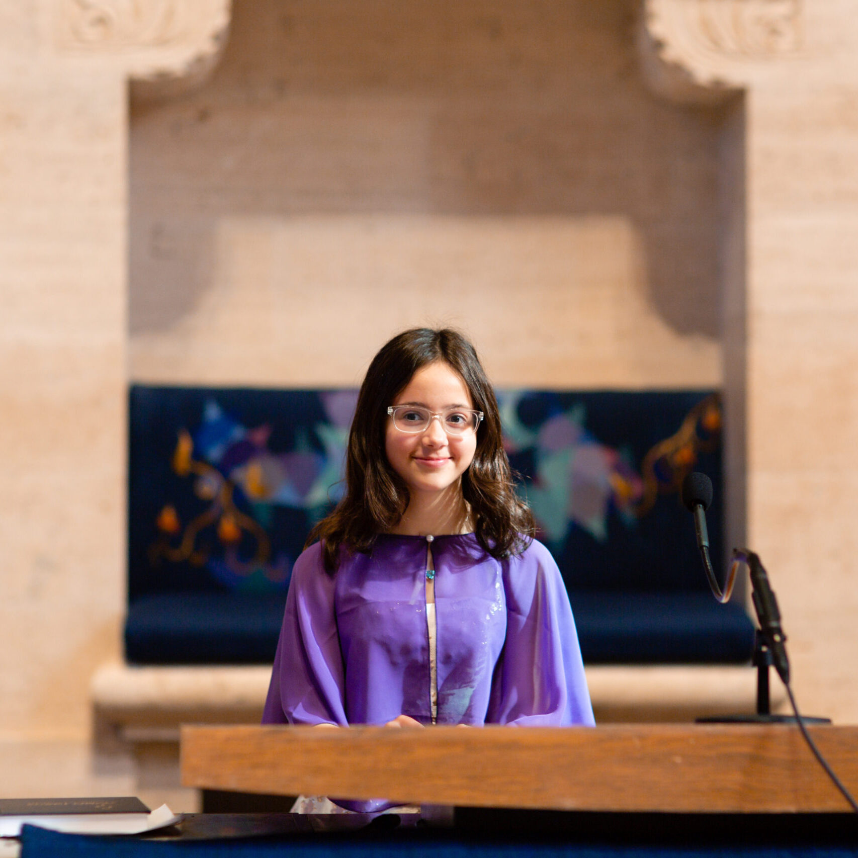 A woman in purple dress standing at podium.