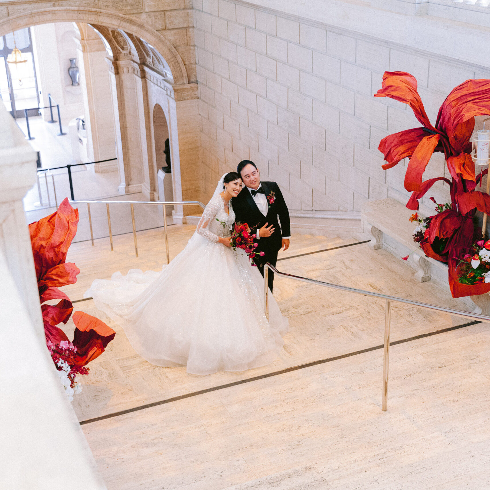 A bride and groom are standing in the middle of an indoor area.