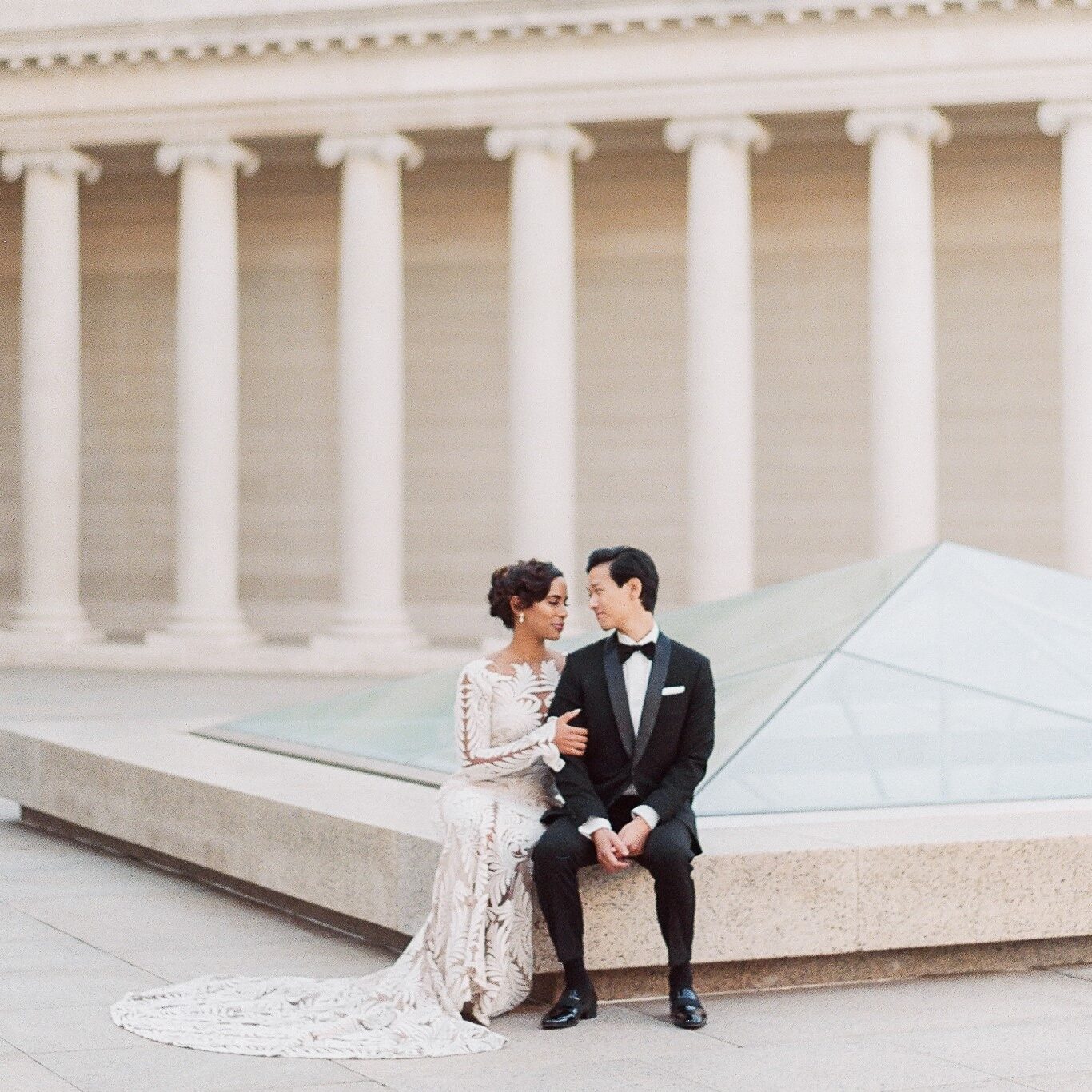 A couple sitting on the ground in front of a building.