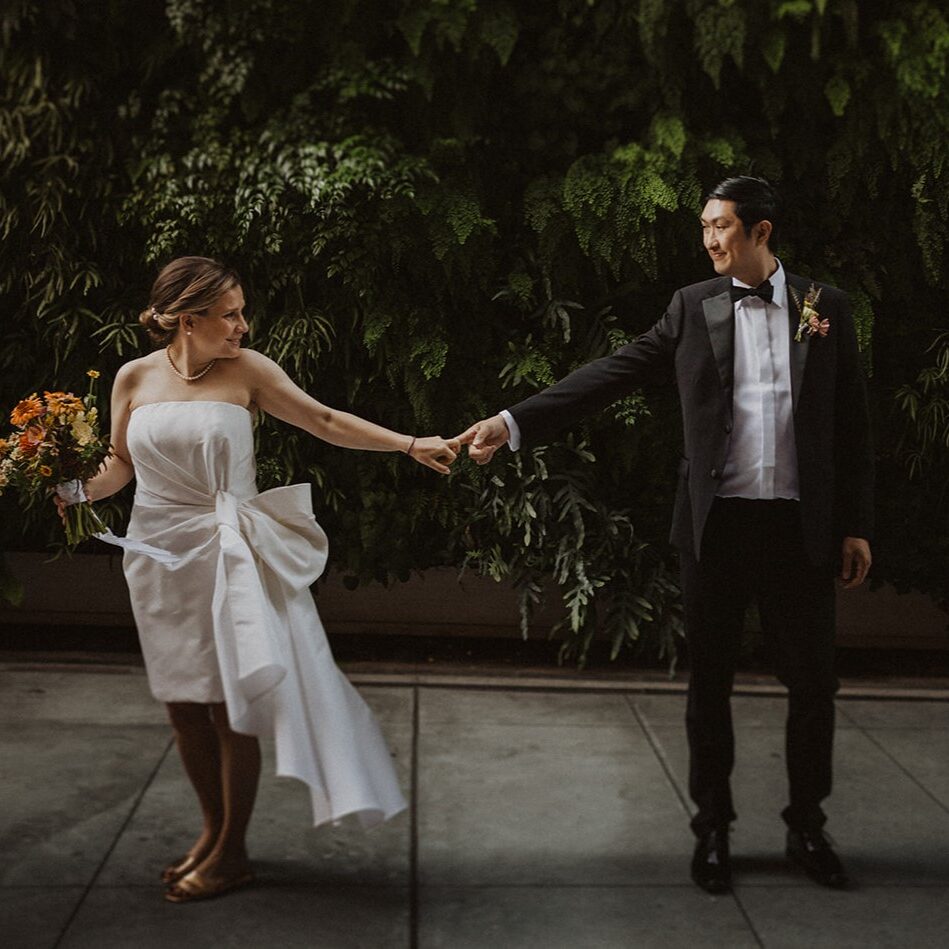 A man and woman holding hands while standing on the sidewalk.