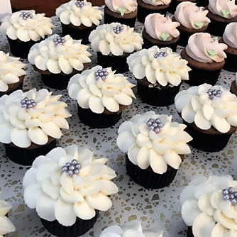 A table topped with lots of cupcakes covered in frosting.