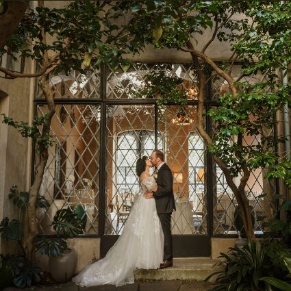 A bride and groom kissing in front of a building.