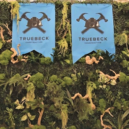 Two blue banners hanging on a wall with plants.