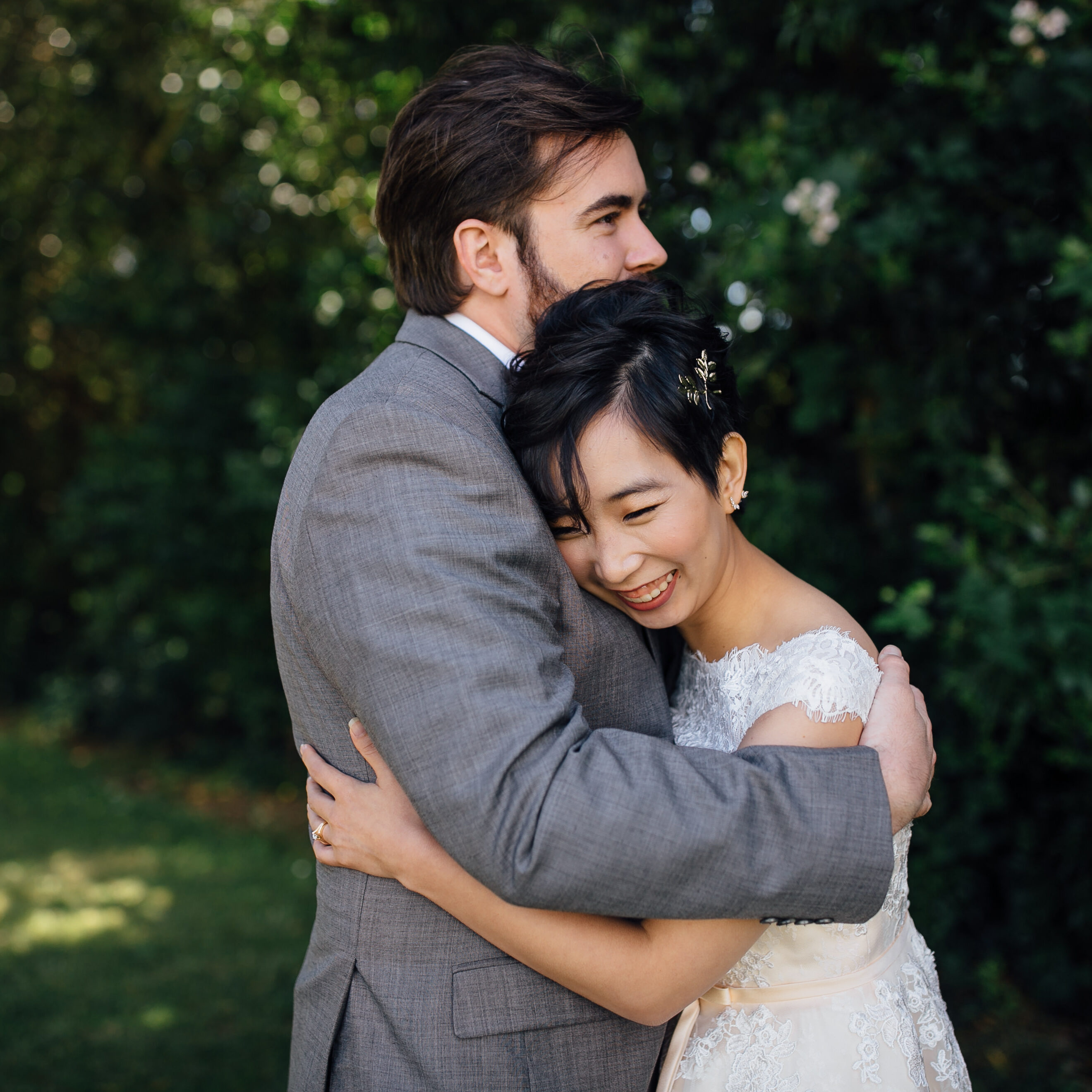A man and woman hugging in front of trees.