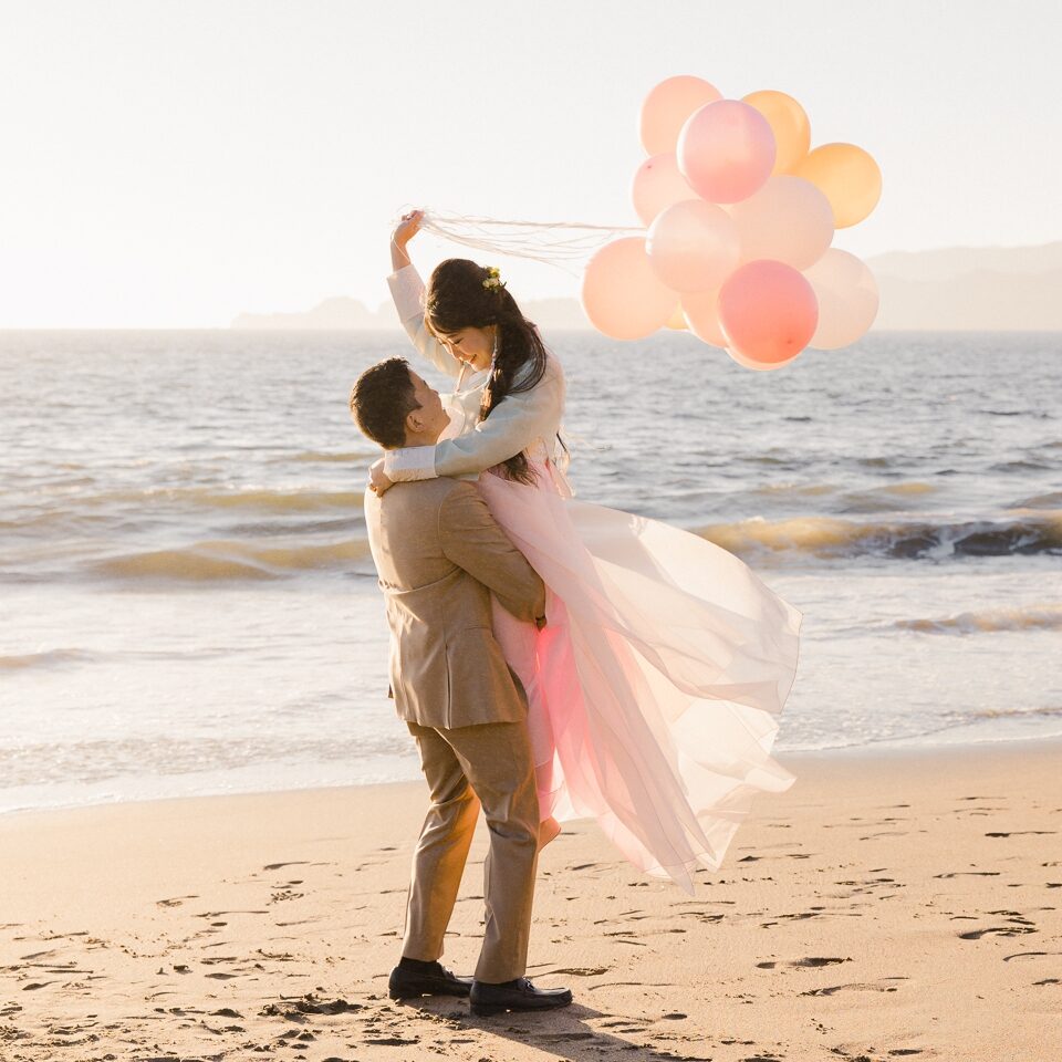 A man and woman on the beach with balloons